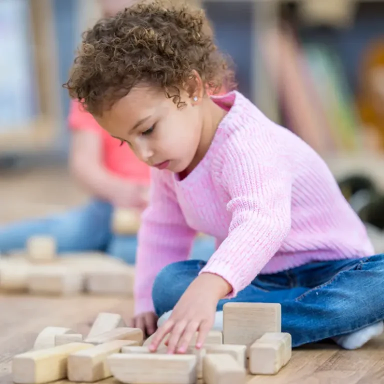 Young child playing with wooden blocks during an Applied Behavior Analysis (ABA) therapy activity.